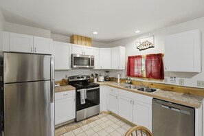 A modern kitchen with white cabinets, stainless steel appliances, a wooden countertop, and a red window treatment. - Peaceful Cabin w/ Hot Tub Near Mt Rainier (Packwood)