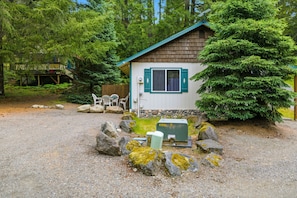 A cabin with a wooden exterior, a window with shutters, and a small porch area. - Peaceful Cabin w/ Hot Tub Near Mt Rainier (Packwood)