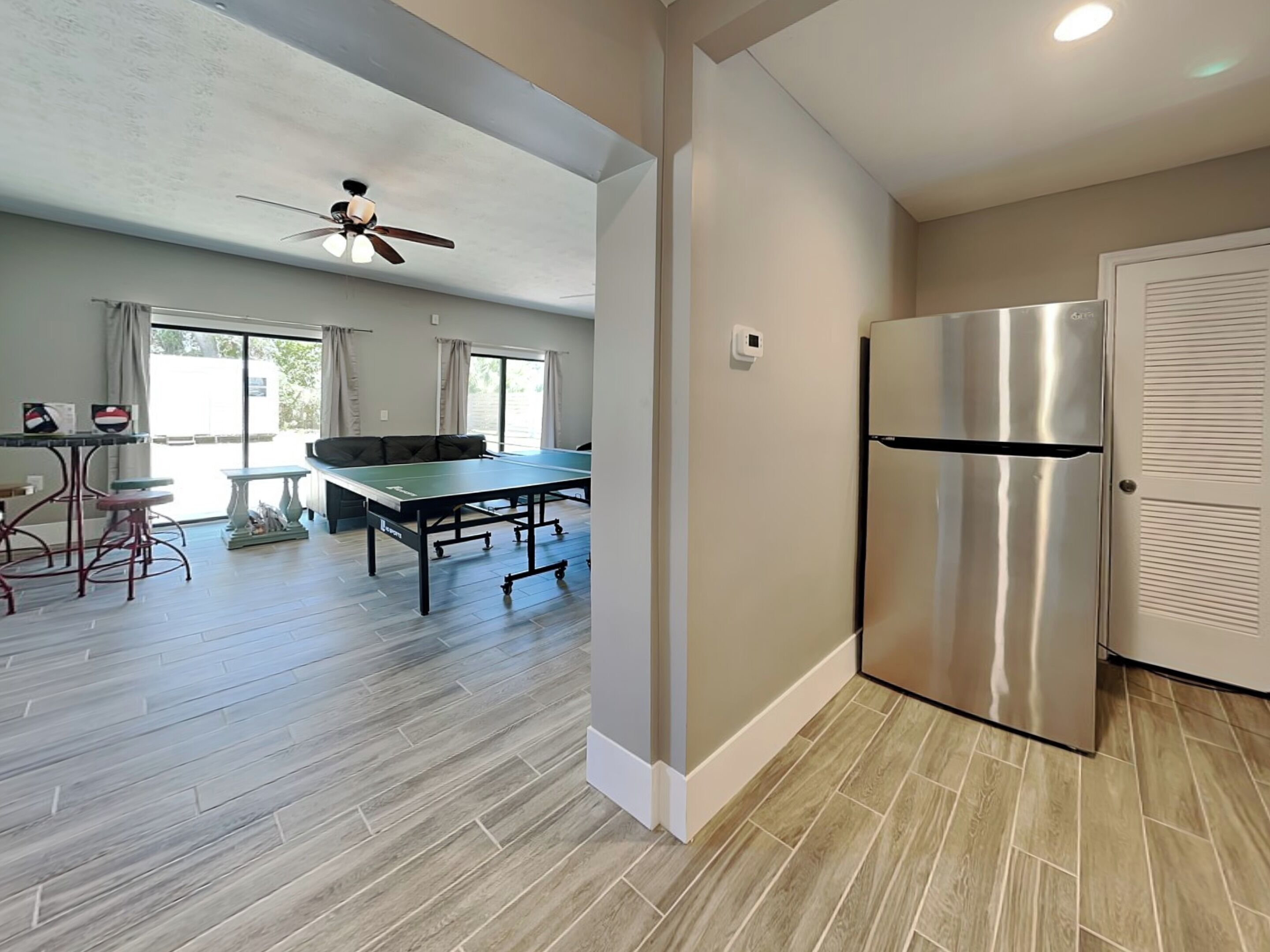Una cocina moderna con un refrigerador de acero inoxidable, una mesa de comedor y un ventilador de techo.