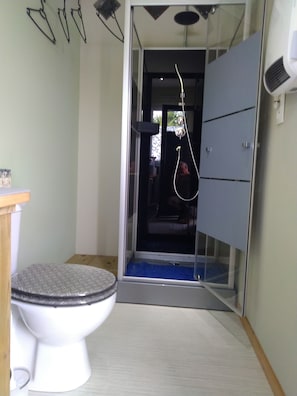 A bathroom with a toilet, a shower enclosure, and a cabinet.