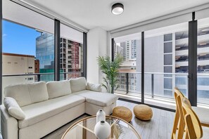 Ein modernes Wohnzimmer mit einer Couch, einem Glastisch und Blick auf eine Parkgarage.