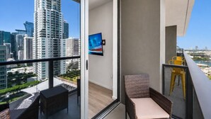 Een balkon met stadszicht, een televisie en tuinmeubilair.