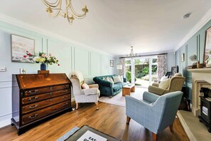 Una sala de estar con un aparador de madera, un sillón azul, un sofá verde y una chimenea.