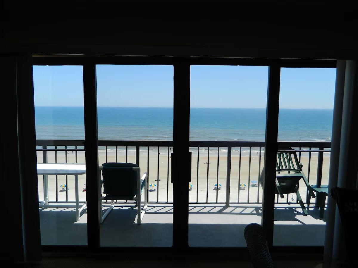 A balcony with a view of the beach and ocean.