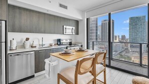 A modern kitchen with a dining area, large windows, and a city view. - Casa Marina – Skyline Views Luxury Downtown Tower (Miami)