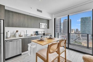 Une cuisine moderne avec un coin repas, de grandes fenêtres et une vue sur la ville.