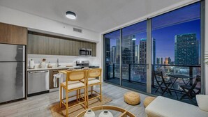 A modern kitchen with a dining area, large windows with a city view, and a balcony with seating. - Casa Marina – Skyline Views Luxury Downtown Tower (Miami)