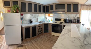 Une cuisine dotée de plans de travail en marbre, d’un four encastré, d’un réfrigérateur et d’armoires en bois.