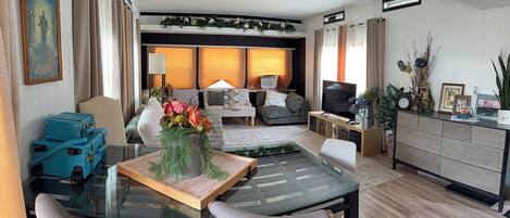 Una sala de estar moderna con una mesa de centro de vidrio, zona de estar y un televisor.