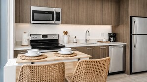 A modern kitchen with a built-in microwave, stove, and stainless steel refrigerator. - Casa Soléa Apartment | Luxe Miami Escape (Miami)