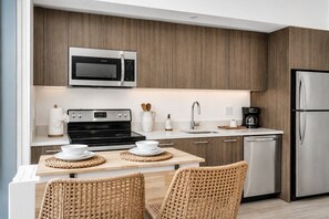 Uma cozinha moderna com micro-ondas integrado, fogão e geladeira de aço inoxidável.