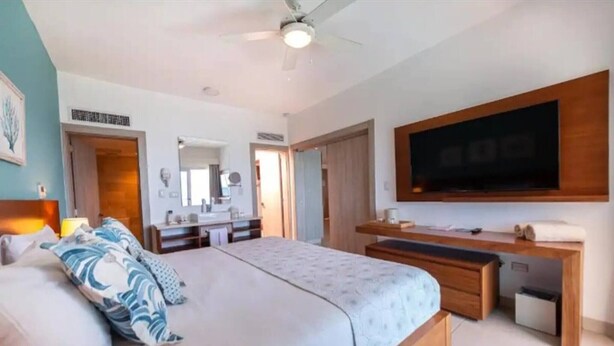 Une chambre à coucher moderne avec un lit, des tables de chevet, une télévision et un bureau.