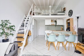 A modern loft-style apartment with a dining area, kitchen, and a staircase leading to a loft bedroom. - Bright apartment NICE CENTRE - 4 pers - Near Beach & Place Masséna (Nice)