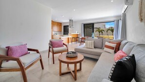 A modern living room with a sofa, chairs, a coffee table, and a kitchen in the background. - Stunning & Beautiful House With Private Pool (Cabo San Lucas)