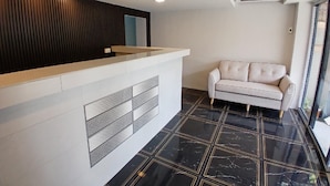 En receptionsdisk med modern design, en vit soffa och ett svart marmorgolv med guldfärgade linjer.