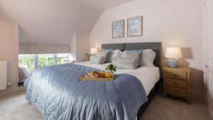 A bedroom with a large bed, bedside tables, a window, and two framed pictures on the wall. - Sun Cottage - Wonderful dog friendly cottage (Kingham)