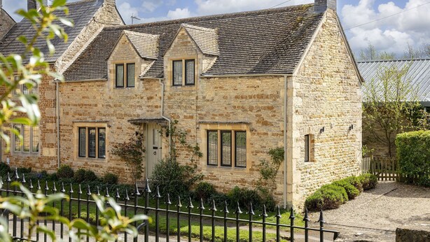 A stone house with a pitched roof, multiple chimneys, and a gated driveway. - Sun Cottage - Wonderful dog friendly cottage (Kingham)