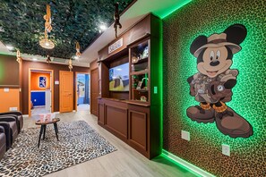 A lobby with a leopard print carpet, a reception desk, and a large cartoon character mural. - 5BR w Pool Grill Game Lounge Indoor Slide 16165 (Clermont)