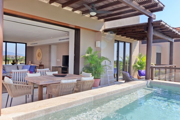 A poolside area with a dining table, chairs, and a potted plant. - Condo Argo in Punta Mita (Punta de Mita)
