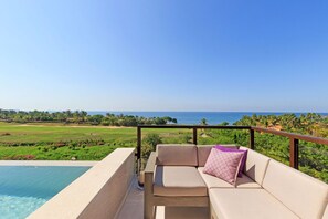 A balcony with a sofa and a glass of beverage, overlooking a golf course and the ocean. - Condo Argo in Punta Mita (Punta de Mita)