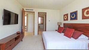 Ein Schlafzimmer mit einem großen Bett, einem Fernseher, einer Holzkommode und einem durch eine offene Tür einsehbaren Badezimmer.