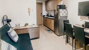 A compact living space with a kitchenette, a dining area, and a seating area. - Cozy 1-bedroom condo in perfect Pasay City with AC (Pasay City)