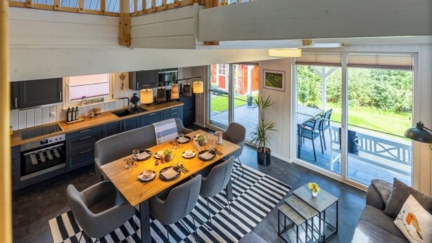 Ein geräumiges Loft mit Essbereich, Küche und einem großen Schiebeglastür zum Außenbereich.