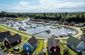 A marina with docked boats, a small dock, and houses with red and blue exteriors. - Quiet time out in the Rotkehlchen vacation home (Wandlitz)