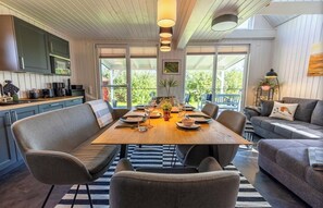 A modern kitchen with built-in appliances, a dining area with a wooden table and chairs, and a cozy seating area with a sofa and armchairs. - Quiet time out in the Rotkehlchen vacation home (Wandlitz)