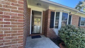 A brick house with a front door, a small porch, and a potted plant. - Beautiful 2-bedroom house with AC in peaceful Palm Valley (Palm Valley)
