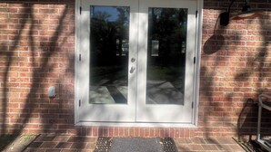 A double door with a glass panel, a brick wall, and a metal shelf with a lamp. - Beautiful 2-bedroom house with AC in peaceful Palm Valley (Palm Valley)