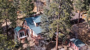 A large house with a green roof, surrounded by trees and a small shed. - Martindale Manor | Historic Mountain Retreat w/ Hot Tub & Game Room (Cascade-Chipita Park)