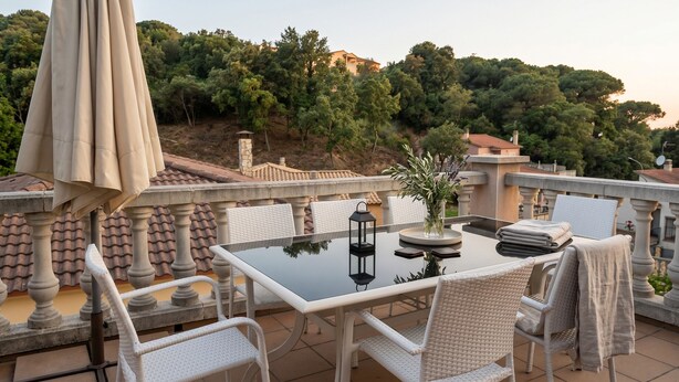 A terrace with a table, chairs, a vase with flowers, and a lantern. - Villa del Lago Lloret - Family Studio | Swimming Pool & Garden (Lloret de Mar)