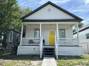 A single-story house with a porch, a yellow door, and a small front yard. - Perfect 3-bedroom house with AC in downtown Tampa neighborhood (Tampa)