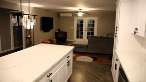 A kitchen with a marble countertop, a ceiling fan, and a television mounted on the wall.