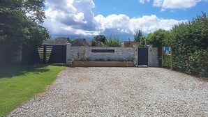 A gravel driveway leading to a gated entrance with a stone wall and a sign reading 'LES CABANES DES LOUPS'.