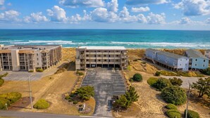 Un hôtel situé sur la côte, doté d’un parking, offrant une vue sur la plage et comprenant plusieurs bâtiments.