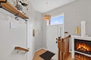 A hallway with a fireplace, a wooden staircase, and a door leading to another room.