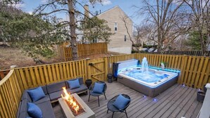 A deck with a hot tub, fire pit, and outdoor seating.