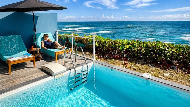 Ein Poolbereich mit Liegestühlen und Blick auf den Ozean.