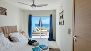 Ein Schlafzimmer mit Bett, Deckenventilator, Meerblick und einer Tür.