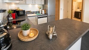 Eine moderne Küche mit Edelstahlgeräten, einem eingebauten Geschirrspüler und einer großen Kochinsel mit Dekorationselementen.
