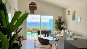 Ein geräumiger Wohnbereich mit Meerblick, einem Deckenventilator und einem Essbereich mit einem runden Tisch.