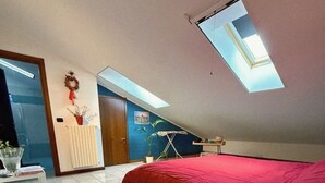 Een slaapkamer met een bed, een bureau, een radiator, een raam en een deur.