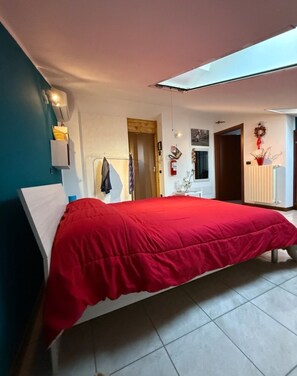 Ein Schlafzimmer mit einem Bett, einem Kleiderschrank, einem Spiegel und einer Tür.