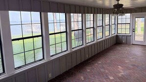 A room with large windows, a brick floor, and a ceiling fan. - Lakeview Lookout - Stunning Views! (Tool)