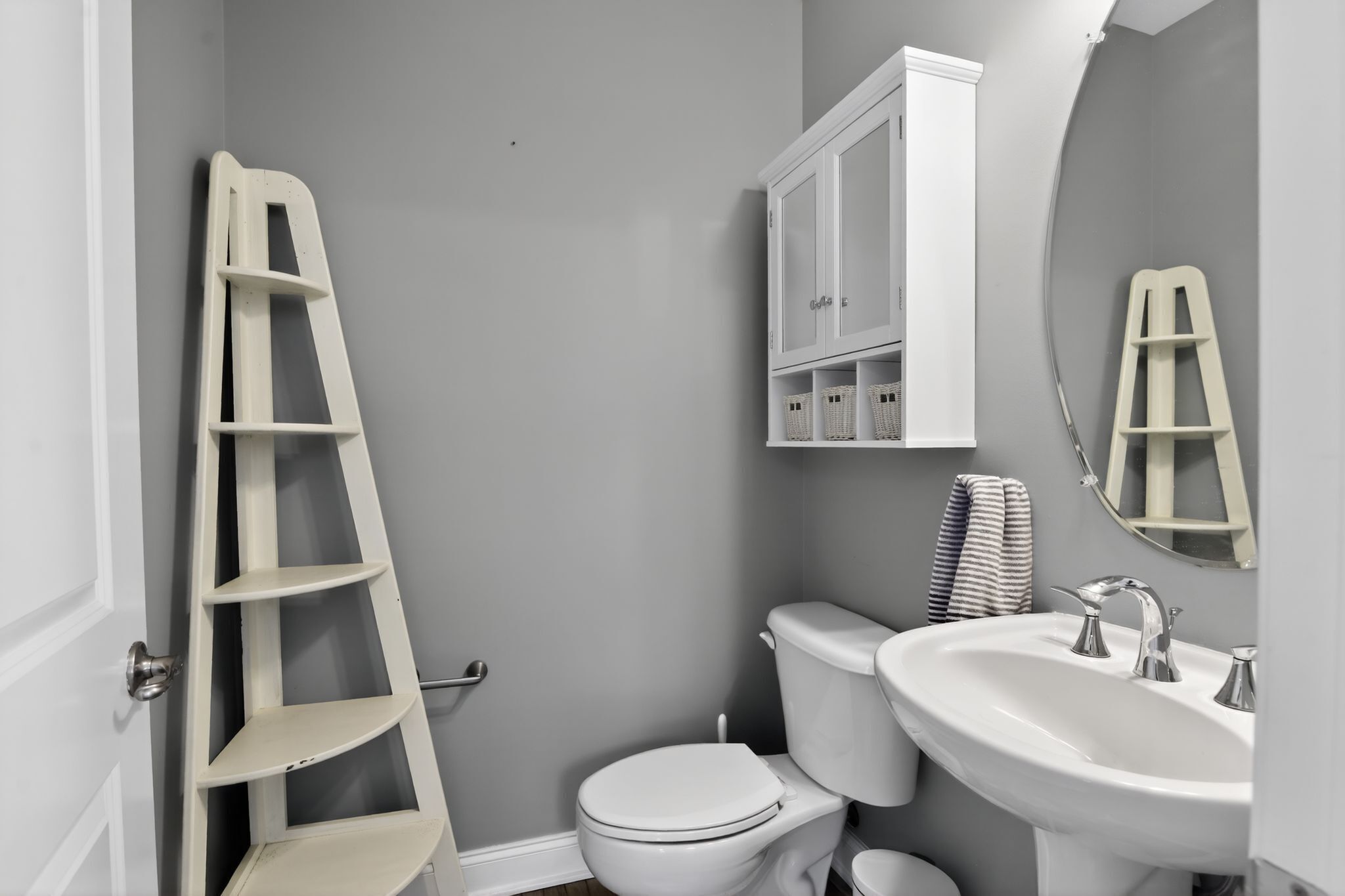 Ein Badezimmer mit Toilette, Waschbecken, einem Schrank und einer Leiter.
