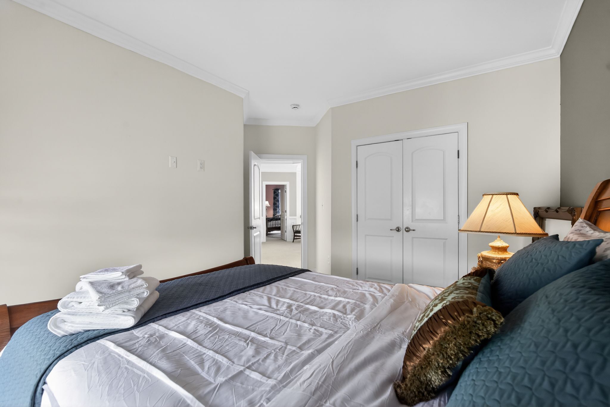 Habitación de hotel con cama, lámpara, puerta y vista al pasillo.