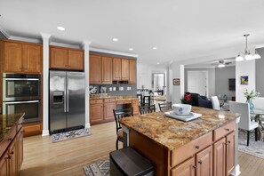 A modern kitchen with wooden cabinets, stainless steel appliances, and a granite countertop island.