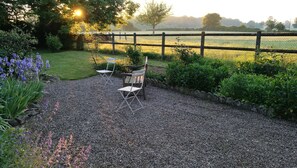 A garden with a gravel path, two folding chairs, and a wooden fence.
